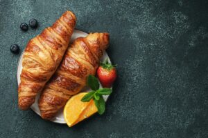 Fresh sweet croissant with butter for breakfast. Continental breakfast on a dark concrete table.